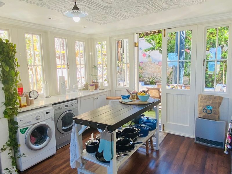 Bright kitchen featuring white cabinetry, timber flooring, and a decorative ceiling, with direct access to the outdoor patio area through glass french doors.