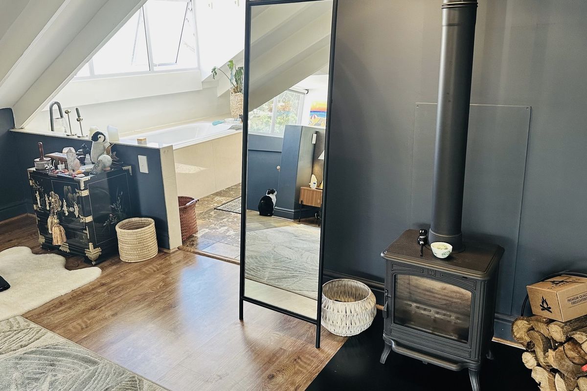 Unique attic-style bathroom featuring a built-in bathtub and a cozy wood-burning stove, creating a warm and functional living space.
