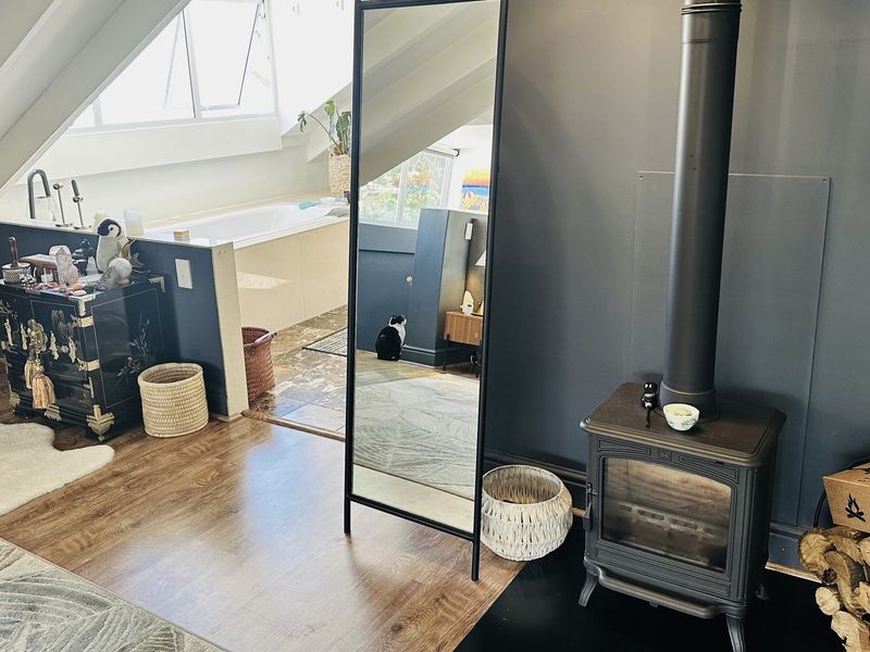 Unique attic-style bathroom featuring a built-in bathtub and a cozy wood-burning stove, creating a warm and functional living space.