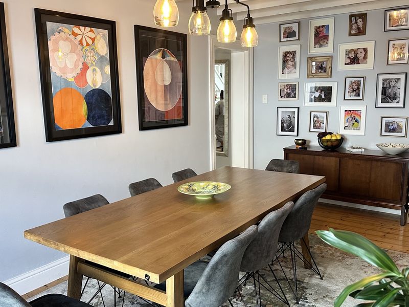 A well-maintained dining room featuring exposed ceiling beams, warm hardwood flooring, and stylish pendant lighting, creating a welcoming space for meals.