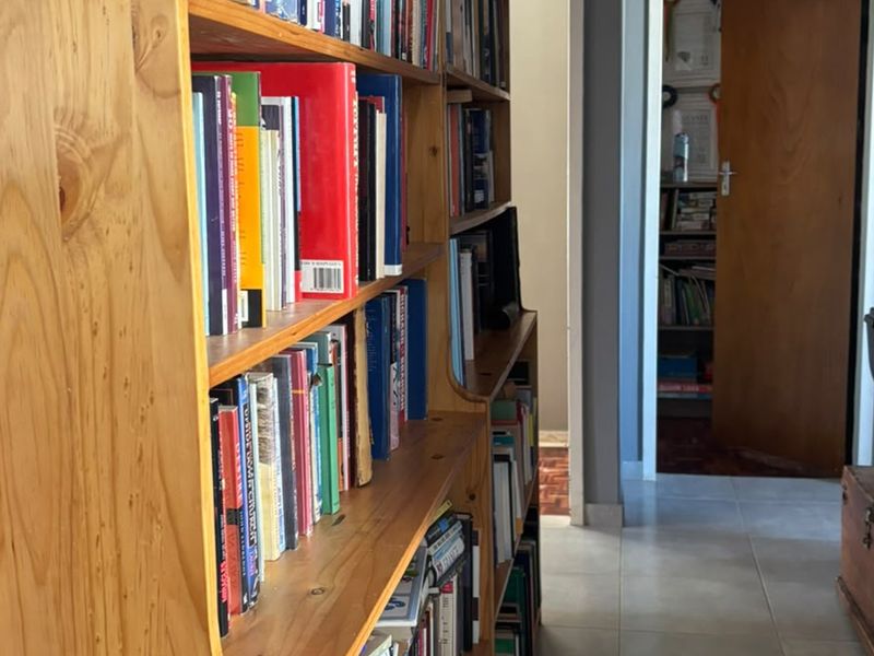 A hallway featuring tiled flooring and built-in wooden shelving units, providing access to adjacent rooms.