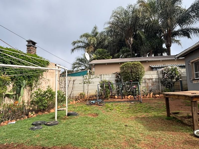 A rear garden area featuring a precast concrete boundary wall, a rotary clothesline, and established trees, providing a functional outdoor space.