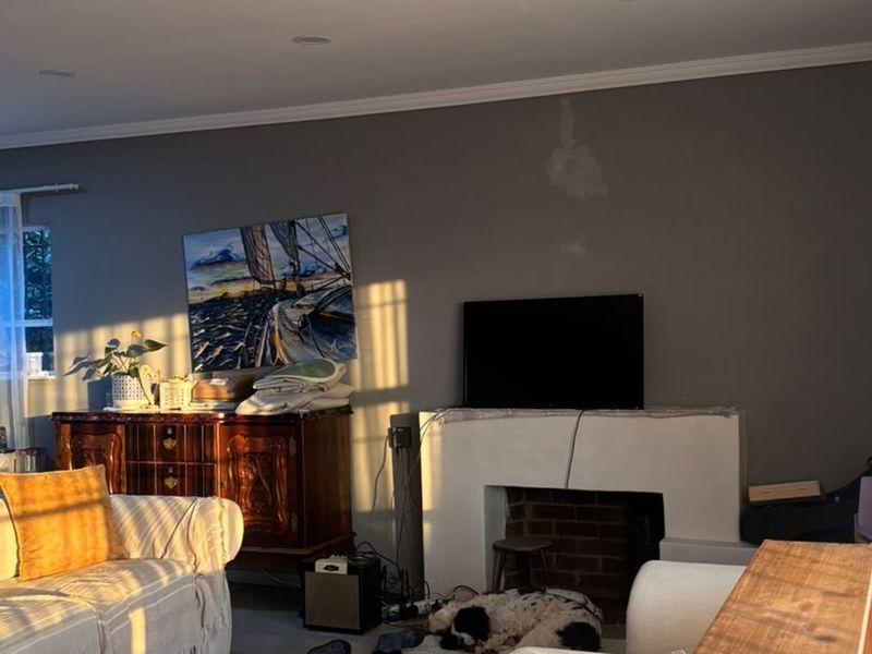 A living room featuring a central fireplace with a brick hearth and crown molding, illuminated by warm natural light.