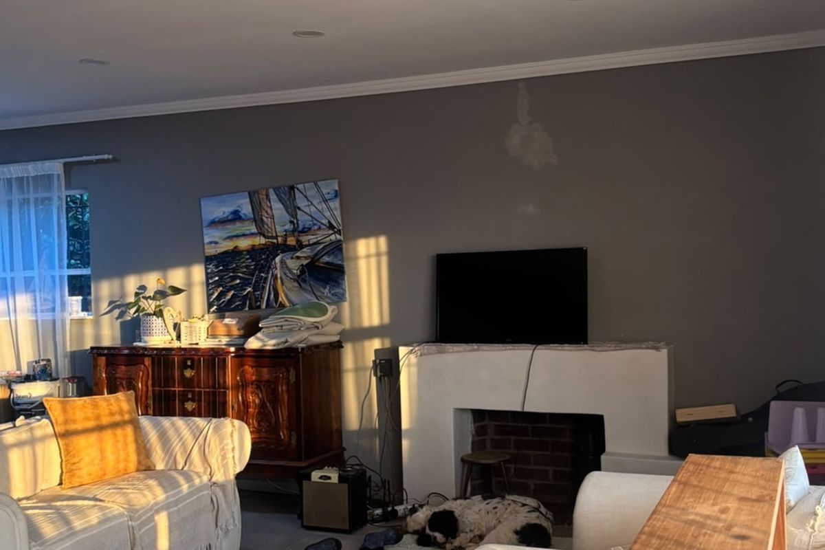 A living room featuring a central fireplace with a brick hearth and crown molding, illuminated by warm natural light.