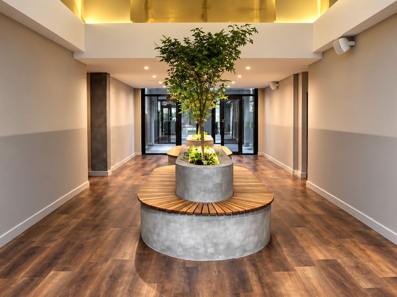 A modern, well-lit hallway featuring wood-look flooring, integrated concrete planters with timber seating, and elegant cove lighting.