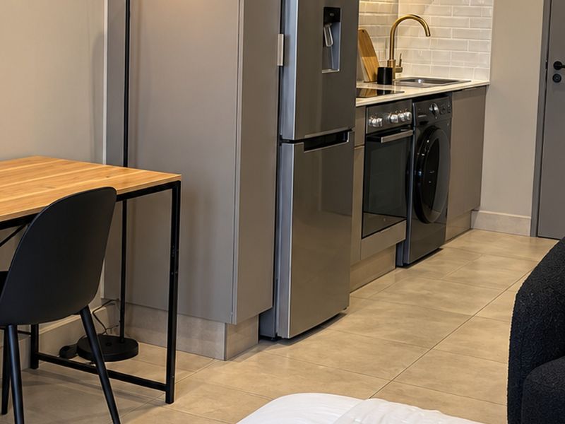 Modern open-plan kitchen area featuring sleek cabinetry, subway tile backsplash, integrated appliances, and contemporary tiled flooring.