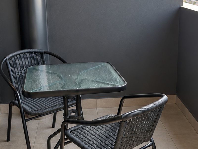 A private balcony featuring neutral tiled flooring and dark-toned walls, providing a compact outdoor space for relaxation.