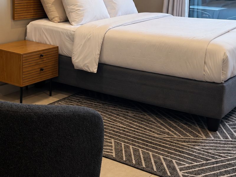 A well-maintained bedroom featuring neutral tones, modern finishes, and access to an outdoor area through a sliding glass door.