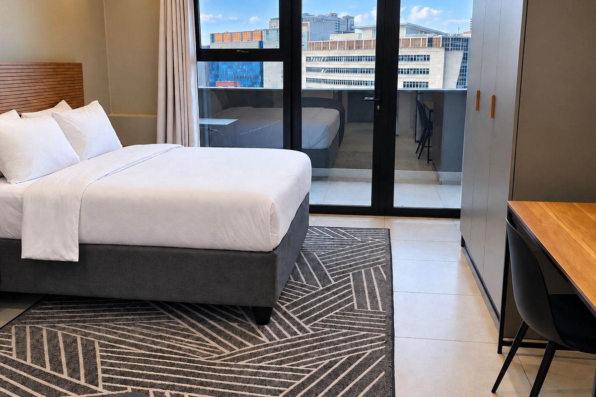 Modern bedroom featuring tiled floors, a built-in wardrobe, and large sliding glass doors providing access to a private balcony with city views.
