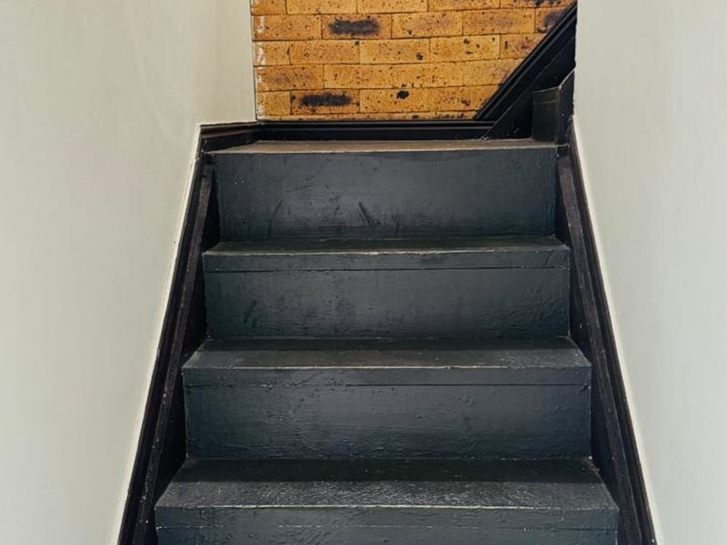 A staircase featuring painted black wooden treads and a decorative exposed brick feature wall.