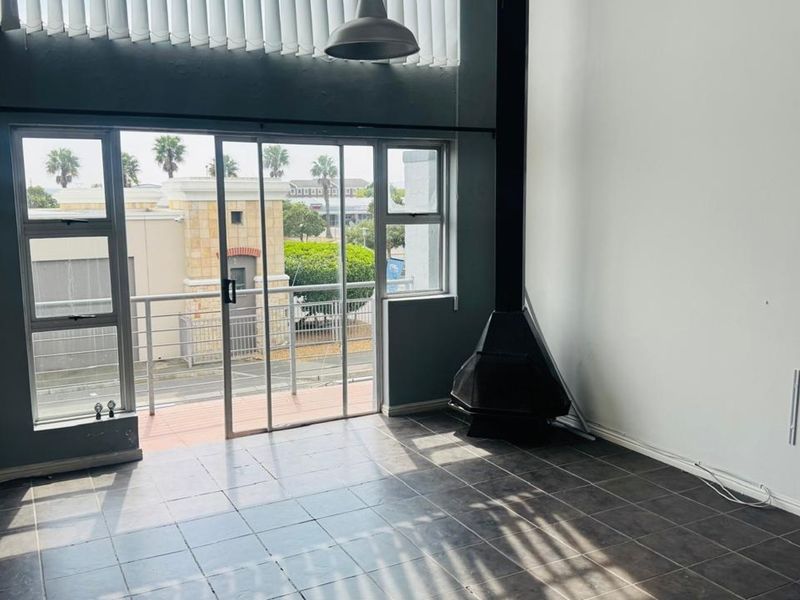 Bright living area featuring tiled floors, a modern freestanding fireplace, and large sliding doors opening onto a balcony with neighborhood views.