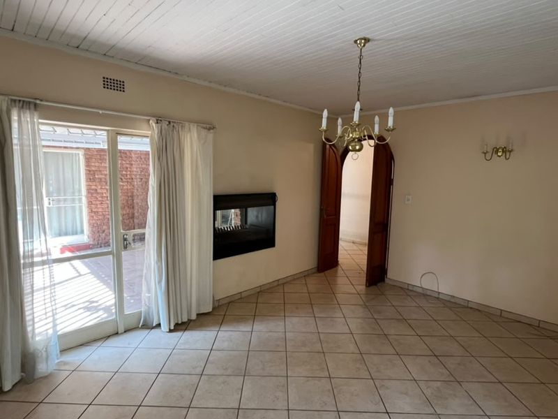 Spacious living room featuring tiled flooring, a built-in fireplace, and a sliding glass door providing access to the exterior patio area.