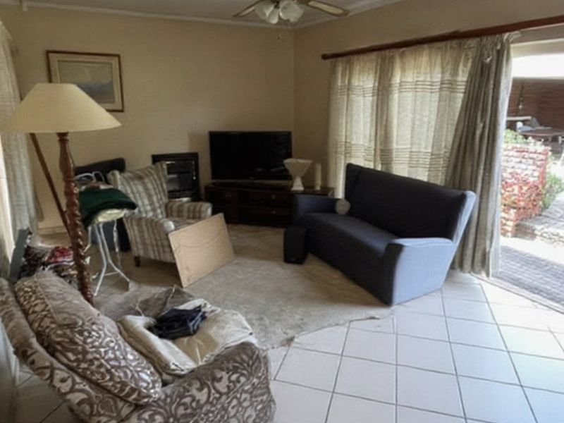 A living room featuring tiled flooring, a ceiling fan, and a sliding glass door providing access to an outdoor patio area.