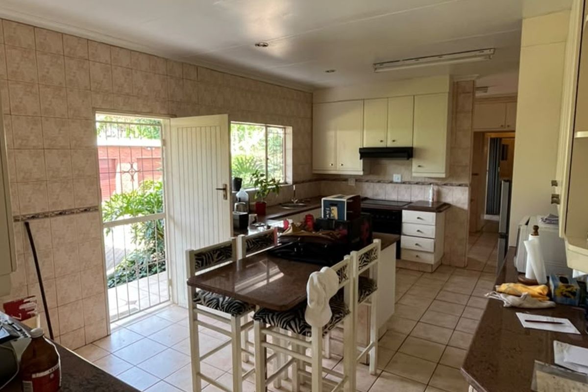 Functional kitchen featuring tiled walls and flooring, built-in cabinetry, and an integrated oven with extractor fan, offering direct access to the exterior.