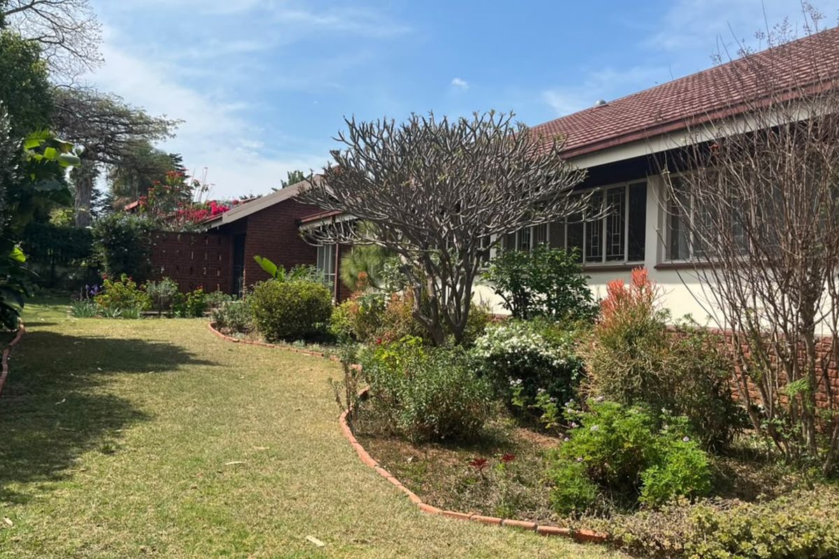 A well-maintained rear garden featuring established landscaping, brick garden edging, and a classic brick facade with a tiled roof.