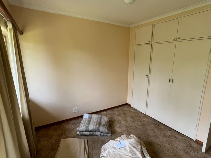 A vacant bedroom featuring built-in cupboards, carpeted flooring, and natural light from the adjacent patio area.