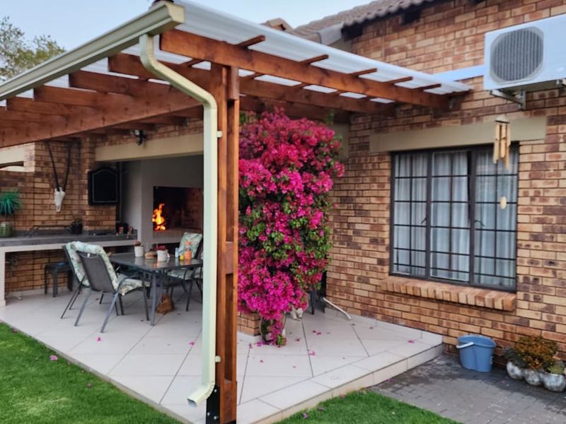 Covered patio area featuring a timber pergola, built-in braai, and tiled flooring, providing an ideal space for outdoor entertaining.