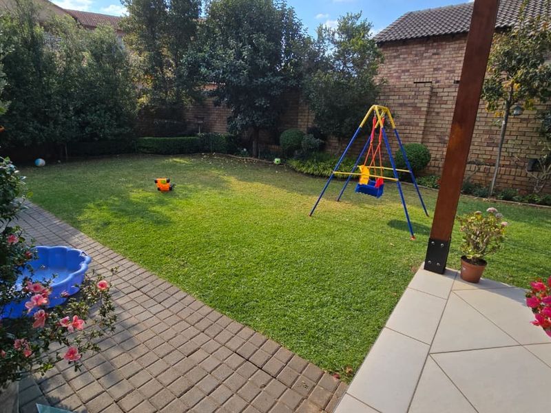 A private rear garden featuring a paved patio area, well-maintained lawn, and established perimeter brick walling.