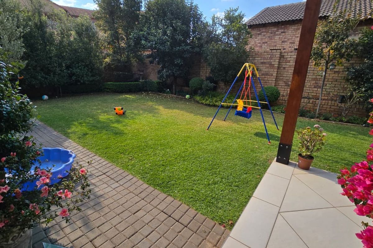 A private rear garden featuring a paved patio area, well-maintained lawn, and established perimeter brick walling.