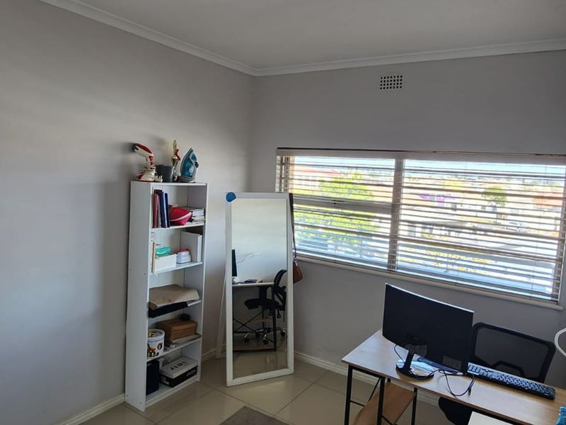 A bedroom featuring tiled flooring, neutral wall finishes, and horizontal window blinds, providing a functional space with natural light.
