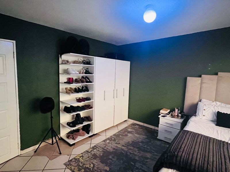 A bedroom featuring dark green walls, tiled flooring, and a built-in wardrobe unit.