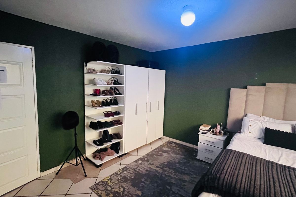 A bedroom featuring dark green walls, tiled flooring, and a built-in wardrobe unit.