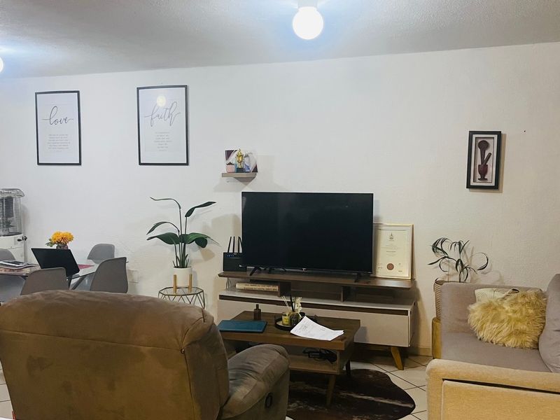 A functional living room area featuring tiled flooring and neutral wall finishes, providing a comfortable space for relaxation and daily living.
