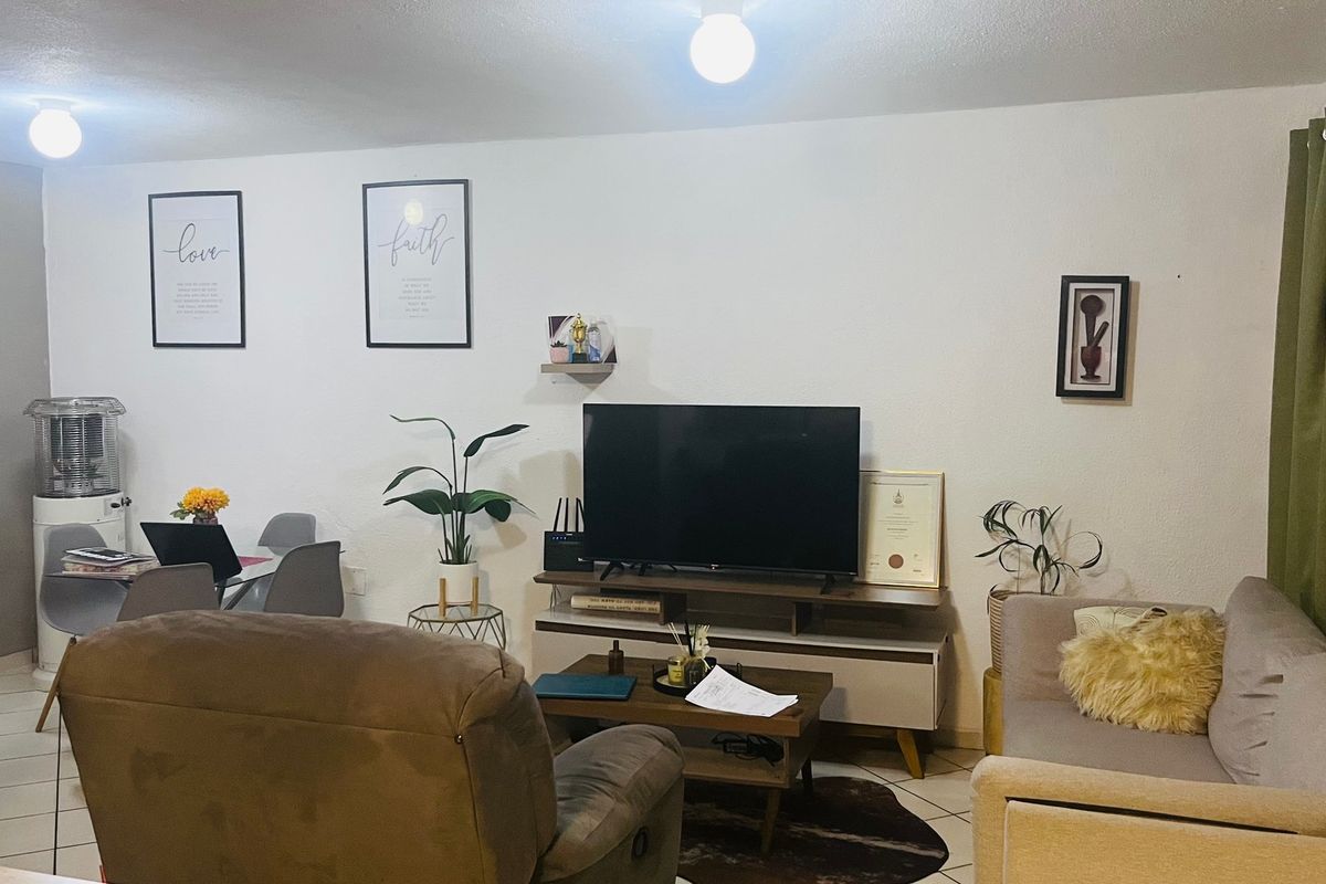 A functional living room area featuring tiled flooring and neutral wall finishes, providing a comfortable space for relaxation and daily living.