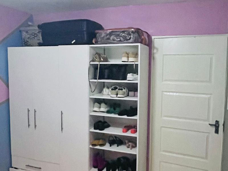 A bedroom featuring a white built-in wardrobe with integrated shelving and a standard interior door.