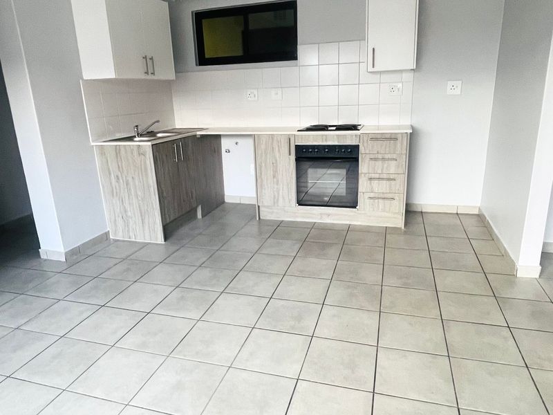 A clean, functional kitchen featuring light wood-look cabinetry, tiled flooring, a built-in oven, and a hob, offering a neutral space ready for personalization.