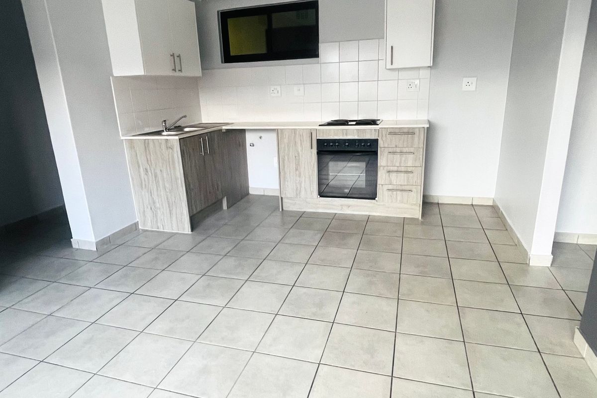 A clean, functional kitchen featuring light wood-look cabinetry, tiled flooring, a built-in oven, and a hob, offering a neutral space ready for personalization.