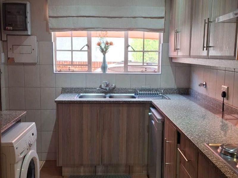 Functional kitchen featuring laminate cabinetry, granite countertops, a double bowl sink, and built-in cooking appliances with tiled splashbacks.