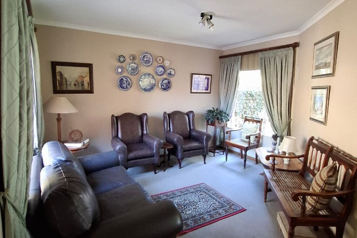 A comfortable living room featuring neutral wall tones, coving, and natural light from the window.