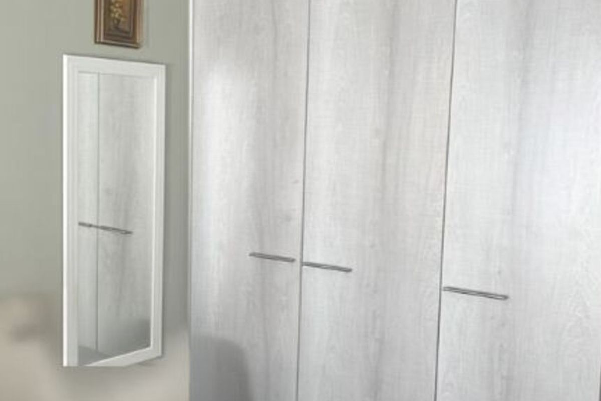 A bedroom featuring a modern light wood-grain built-in wardrobe with sleek metal handles.