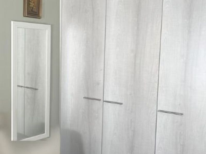 A bedroom featuring a modern light wood-grain built-in wardrobe with sleek metal handles.