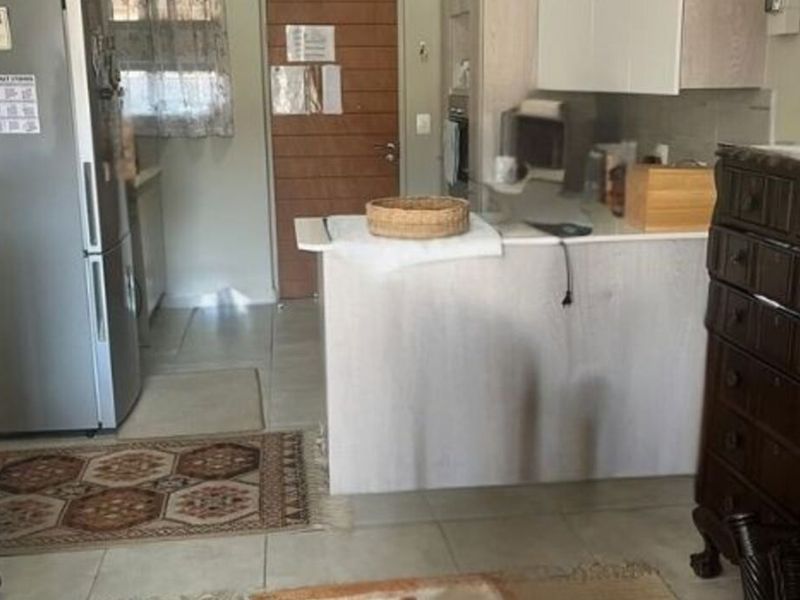 Open plan kitchen area featuring built-in cabinetry, a breakfast counter, and tiled flooring, seamlessly connecting to the living space.