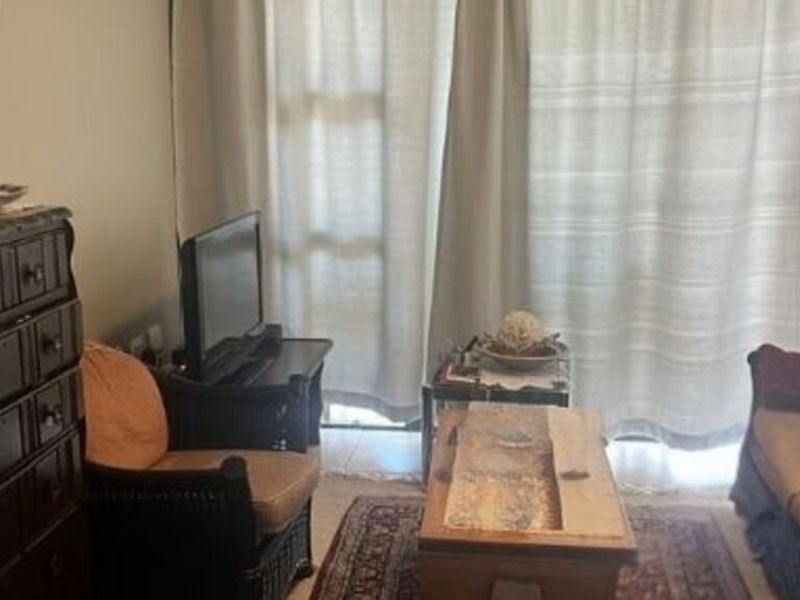 A living room area featuring tiled flooring and a large sliding glass door providing access to the exterior.