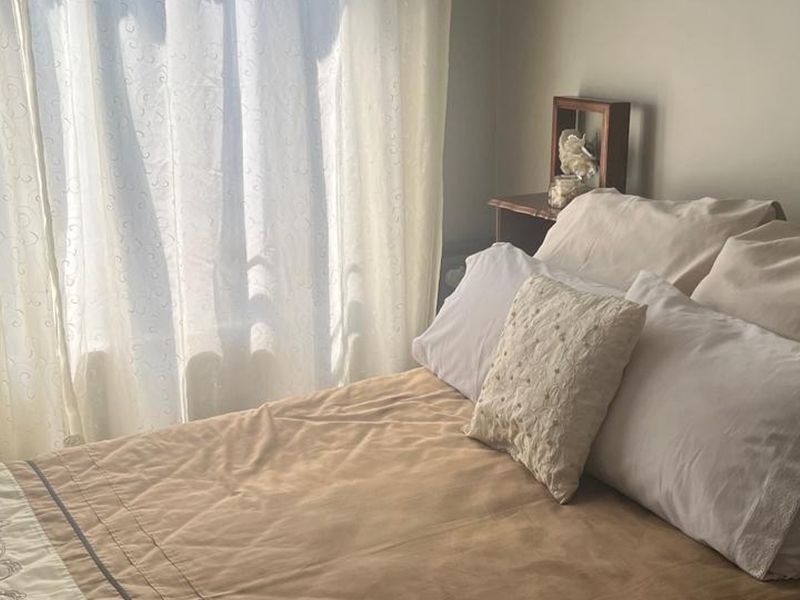 A cozy bedroom featuring natural light from a window with sheer curtains.