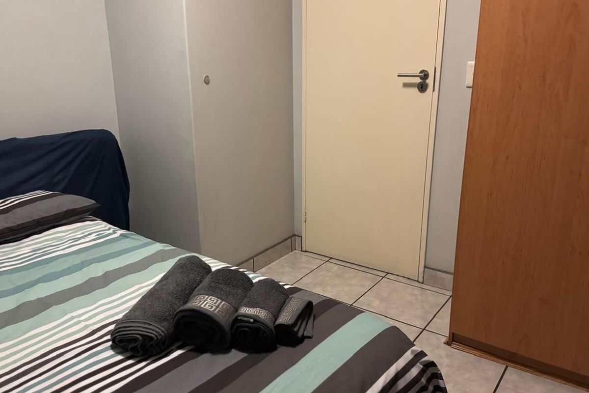 A bedroom featuring tiled flooring and a built-in cupboard, providing functional storage space.