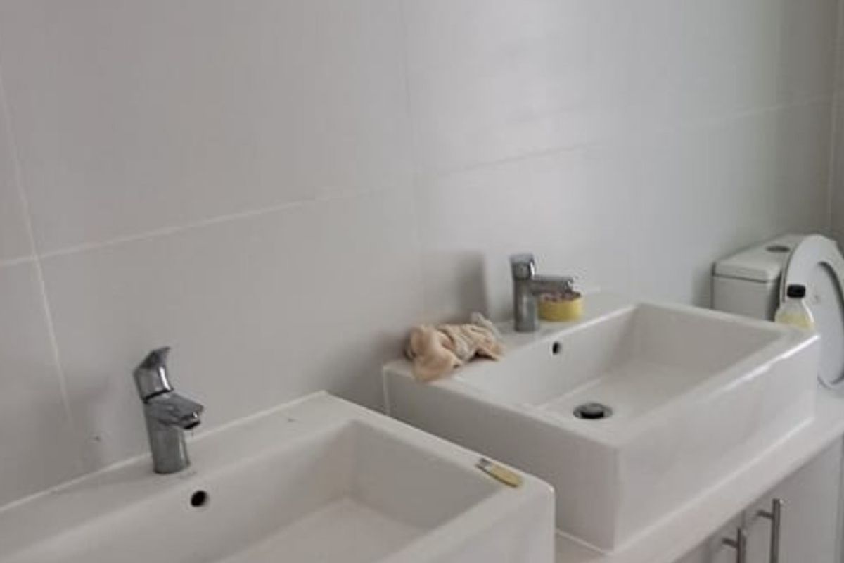 A modern bathroom featuring a double vanity with ceramic basins, chrome faucets, and neutral wall tiling.