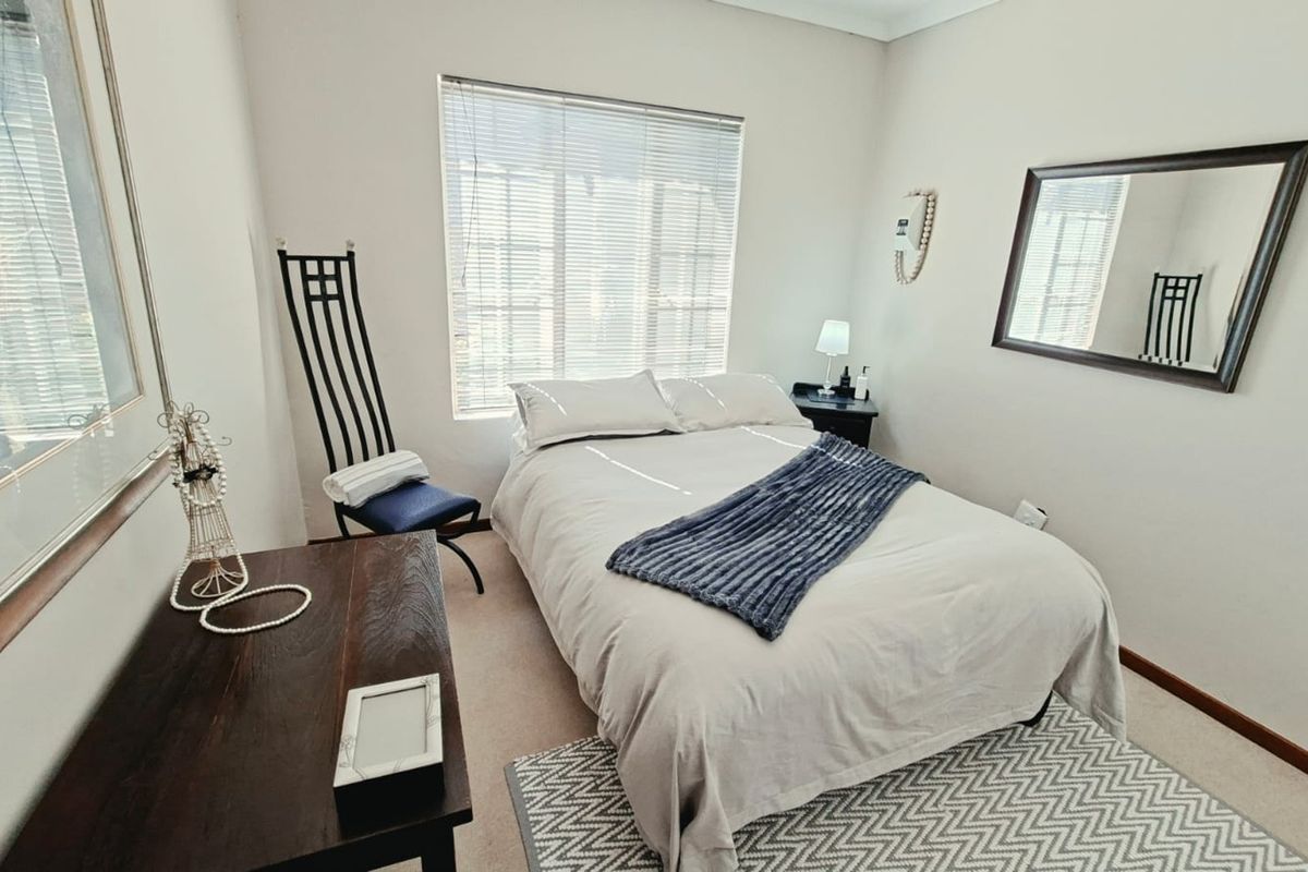 A well-maintained bedroom featuring neutral walls, carpeted flooring, and venetian blinds, providing a comfortable and functional living space.