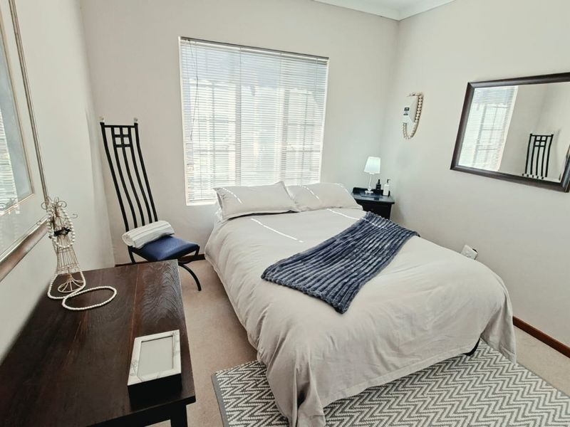 A well-maintained bedroom featuring neutral walls, carpeted flooring, and venetian blinds, providing a comfortable and functional living space.