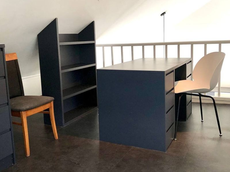 A loft-style office space featuring a sloped ceiling and a protective railing overlooking the lower level.