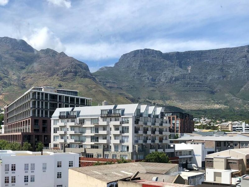 Elevated urban view overlooking surrounding apartment buildings with a prominent mountain range backdrop.