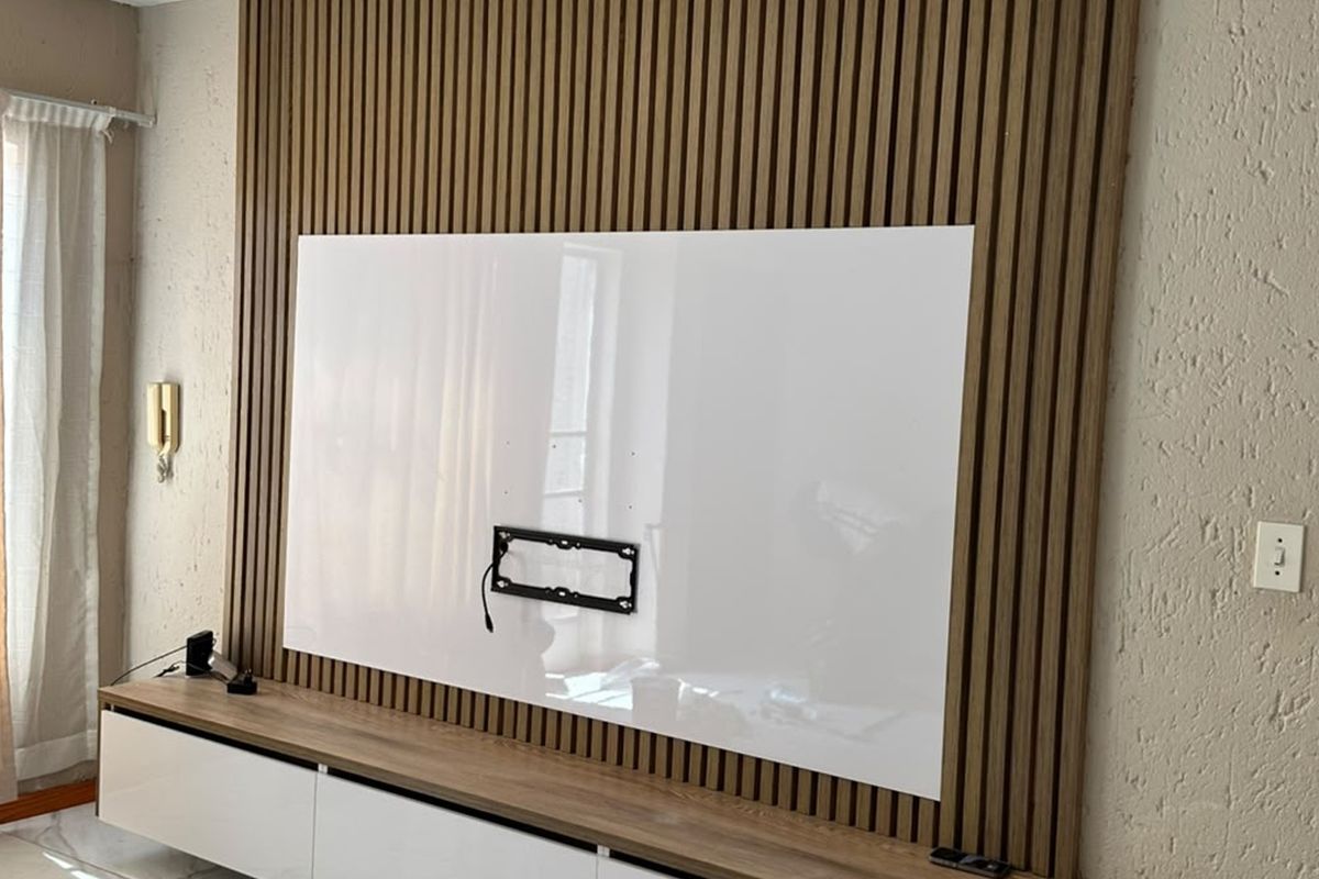 A modern living room feature wall showcasing vertical slatted wood paneling, a built-in media console, and a dedicated wall-mounted television bracket.