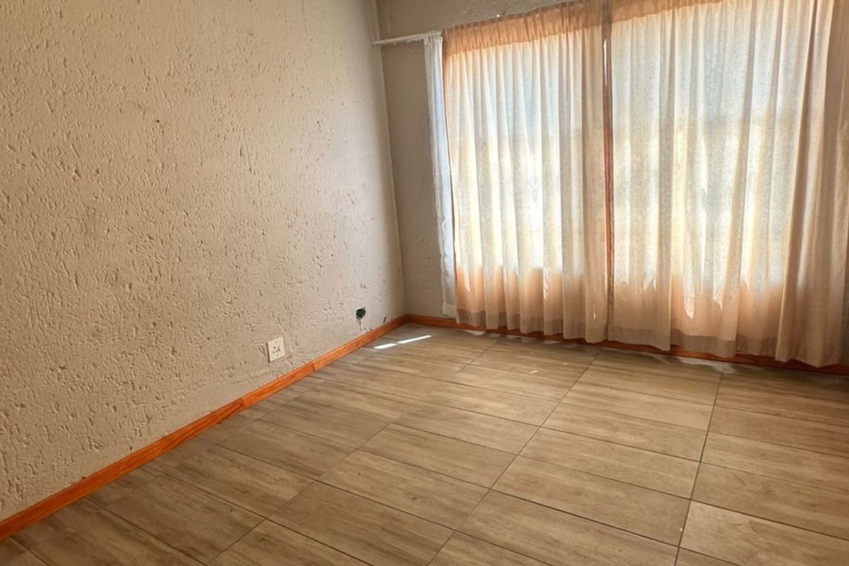 An empty bedroom featuring tiled flooring and textured walls, offering a blank canvas for renovation or interior design updates.