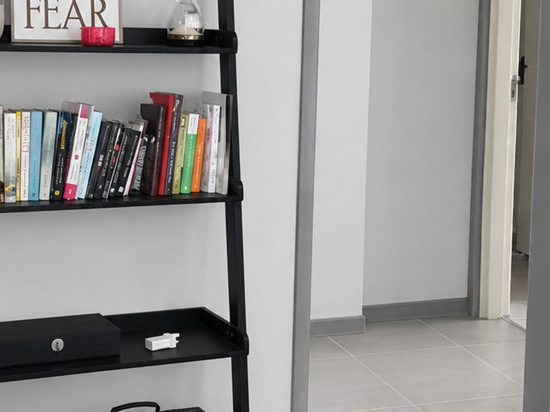 A view of a hallway featuring neutral tiled flooring, grey skirting boards, and a doorway leading to an adjacent room.