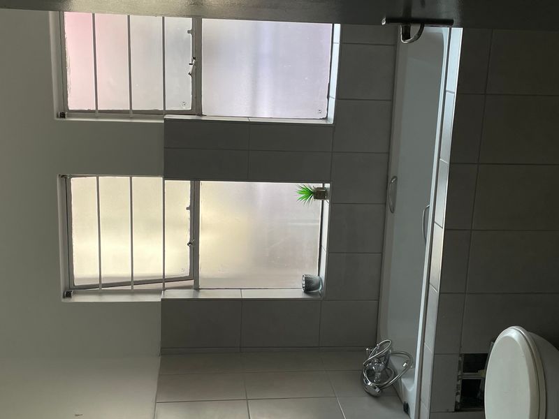 A functional bathroom featuring a bathtub, toilet, and tiled finishes. The space is ready for updates to improve its overall aesthetic and condition.
