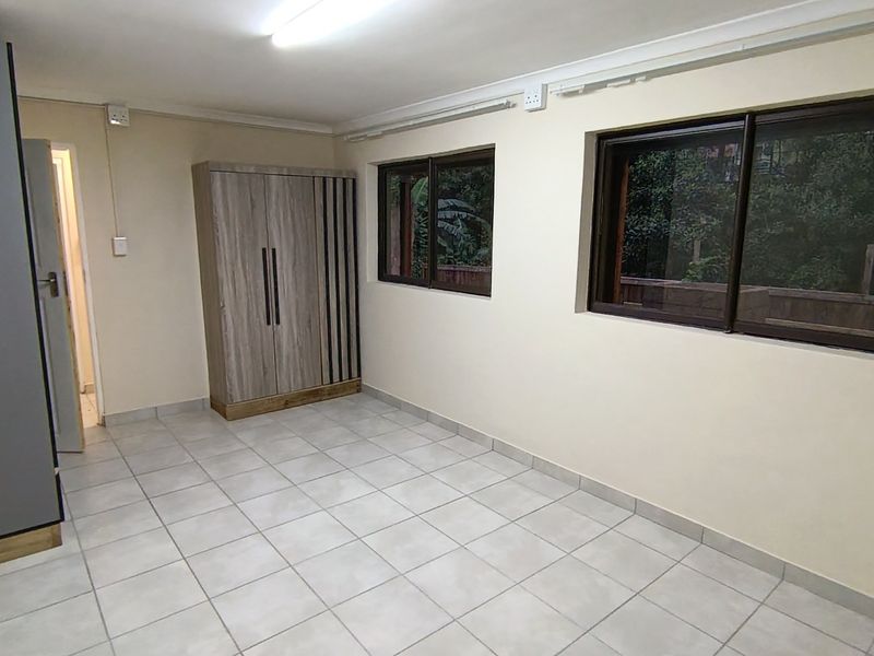 A clean, empty bedroom featuring neutral tiled flooring, sliding windows, and simple coving, providing a blank canvas for personalization.