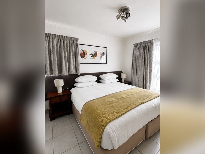 A functional bedroom featuring tiled flooring and a ceiling-mounted spotlight fixture, providing a neutral base for personalization.